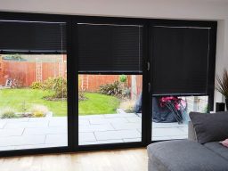 an image of black-framed glass doors with roller blinds partially closed.